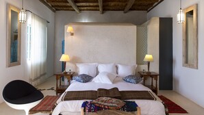 Un dormitorio con una cama grande, dos mesitas de noche con lámparas, una silla y techo de madera.