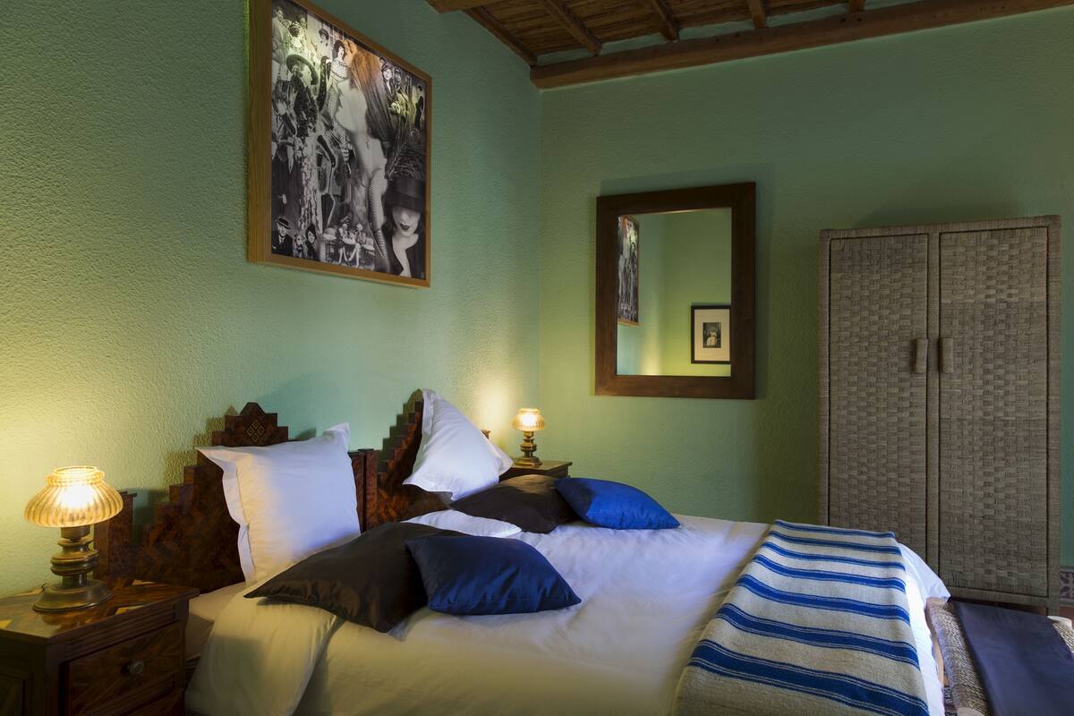 A bedroom with a bed, nightstands, a lamp, a mirror, and a wardrobe.