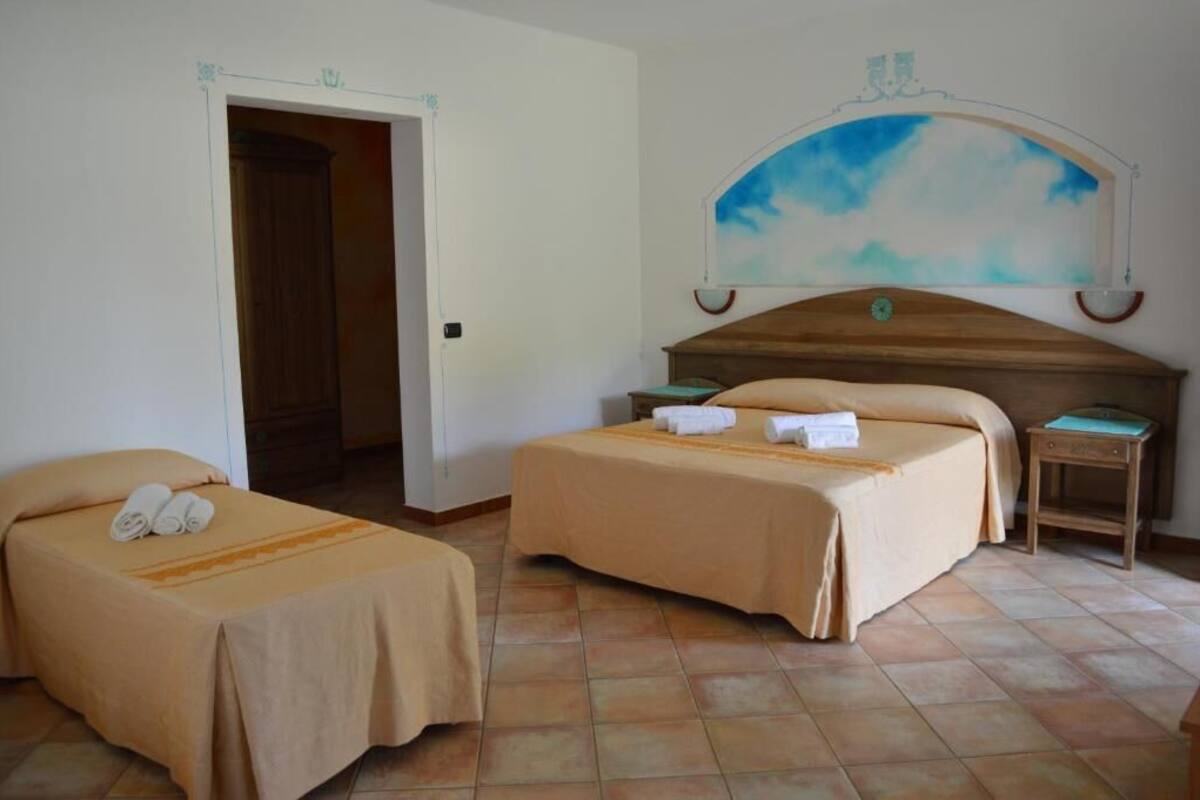 Ein Hotelzimmer mit zwei Betten, einem Holz-Kopfteil, einem Himmelbild und einer Tür.