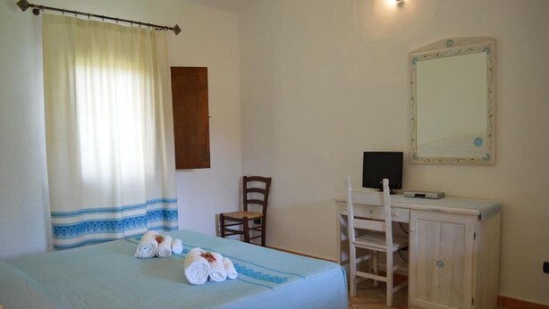 Une chambre à coucher comprenant un lit, un bureau avec une chaise, un miroir et une armoire.