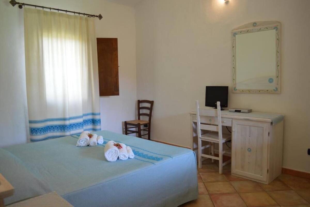 Ein Schlafzimmer mit einem Bett, einem Schreibtisch mit Stuhl, einem Spiegel und einem Schrank.