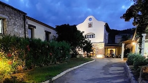 Un edificio con fachada de piedra, una ventana central arqueada y exterior blanco.