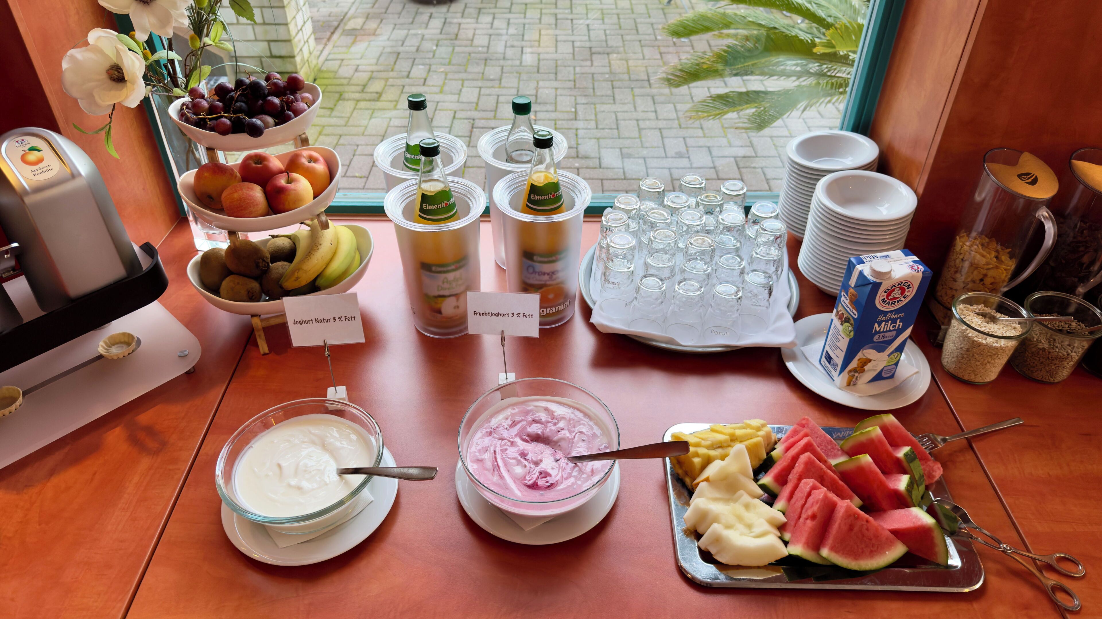 En frukostbuffé med ett urval av olika frukter, yoghurt och juicer.
