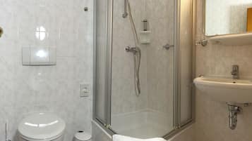 Un baño con inodoro, ducha con cerramiento de vidrio y lavabo.