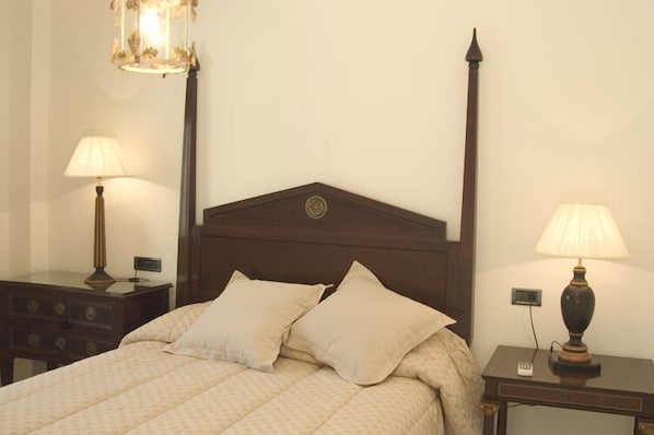 A neatly made bed with two pillows, a wooden headboard, and two bedside lamps on either side.
