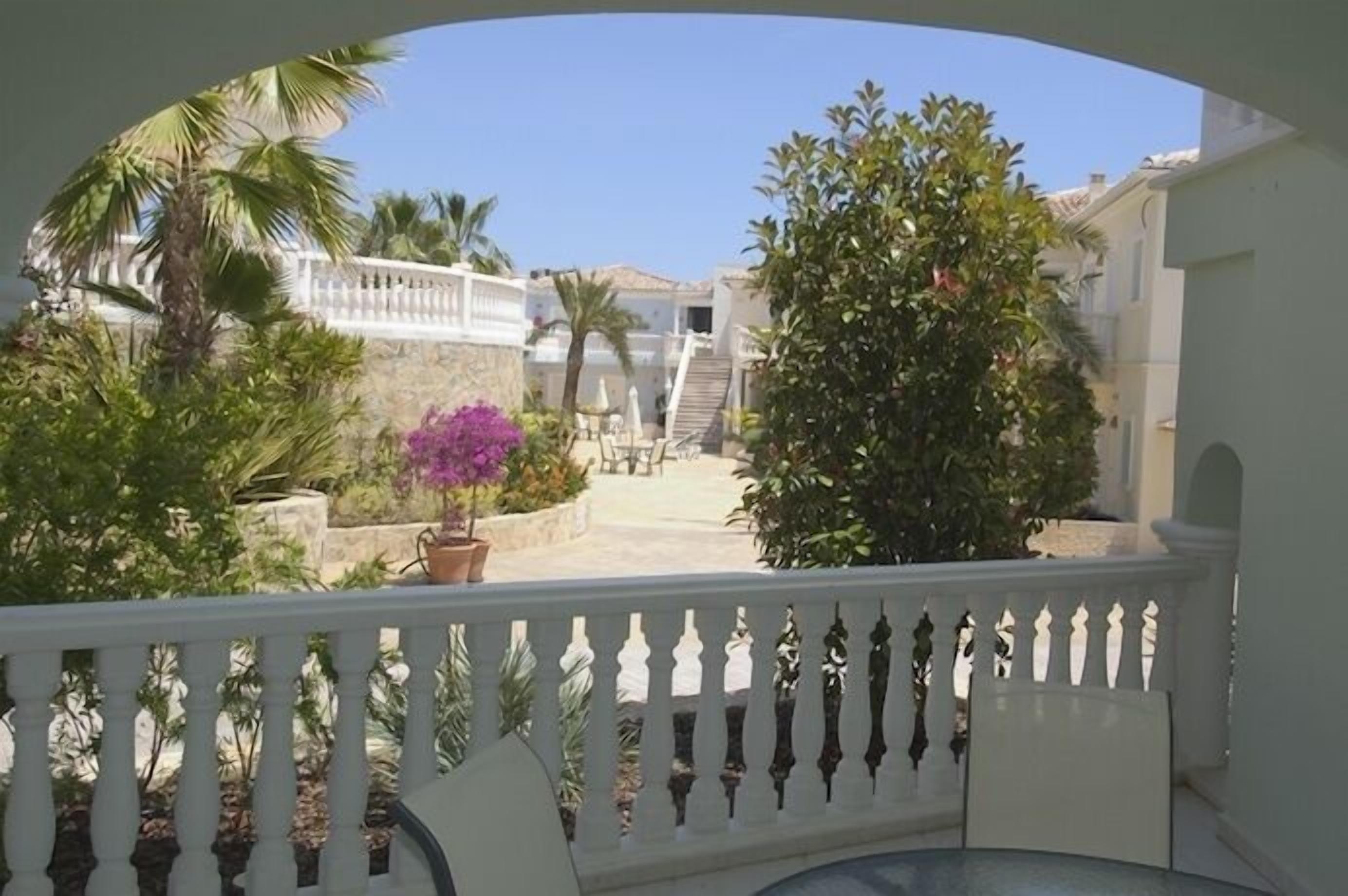 A balcony with a view of a courtyard, including a staircase and potted plants.