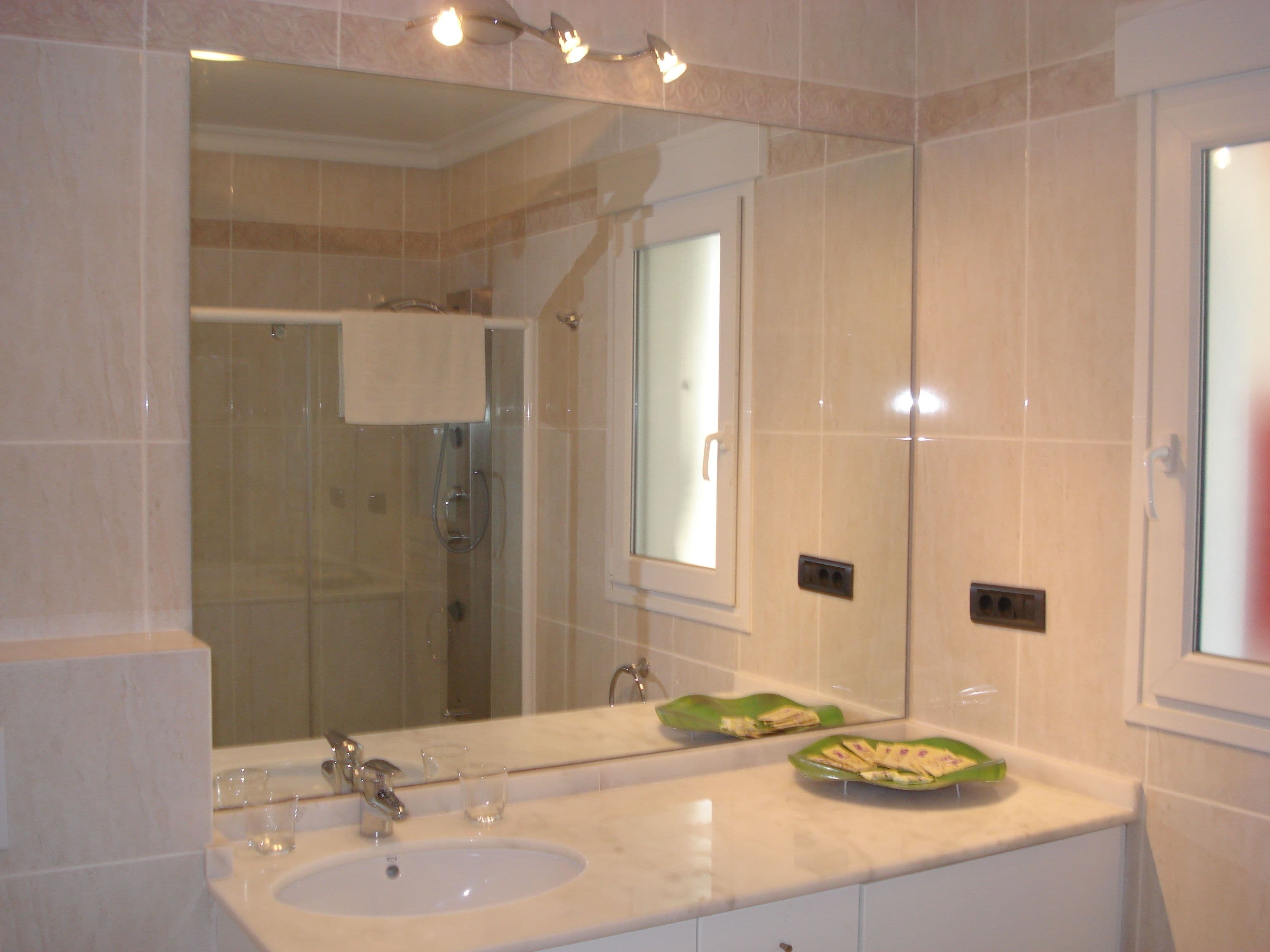 A bathroom with a large mirror, two sinks, and a shower area.