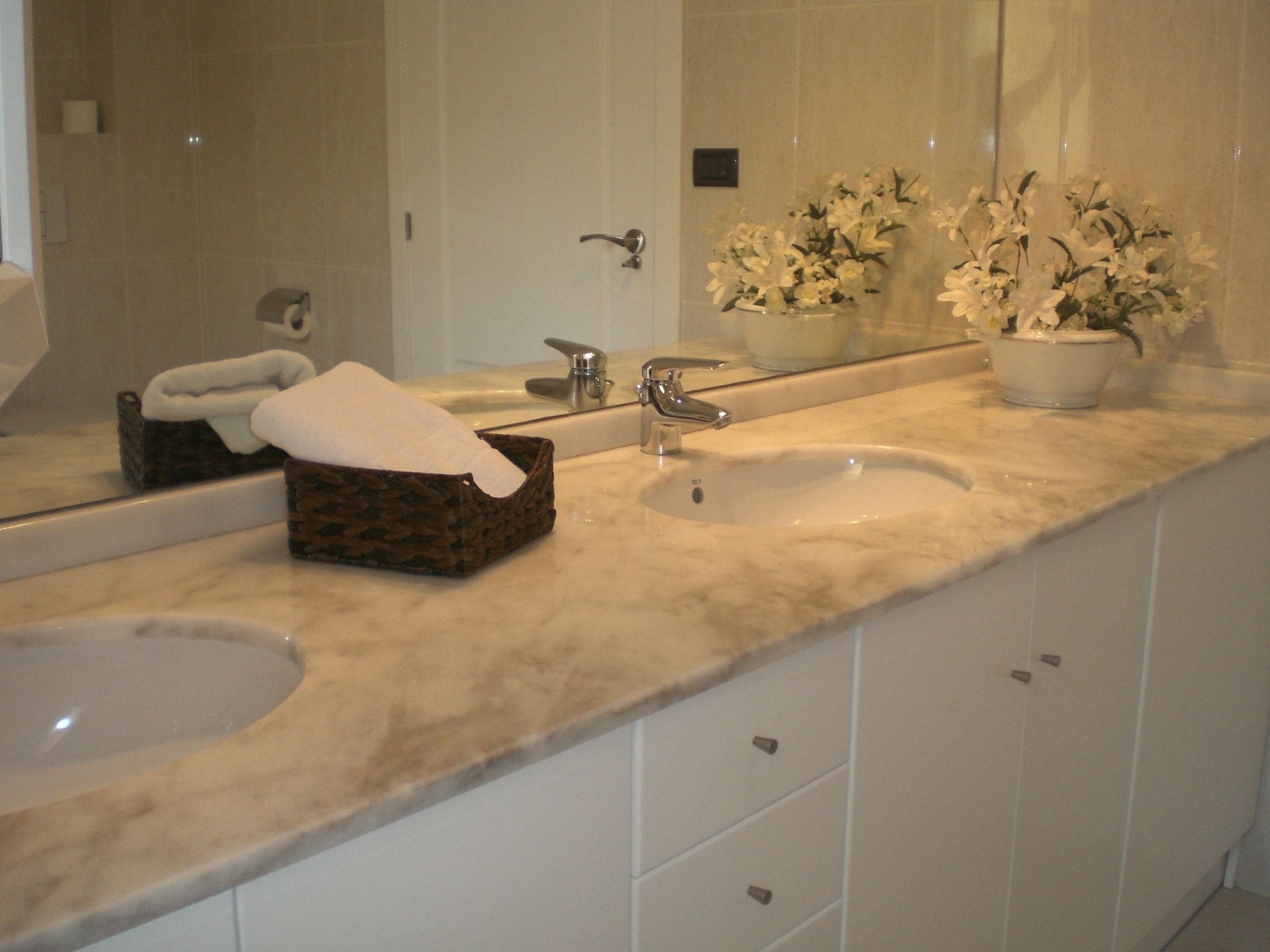 A bathroom with two sinks, a mirror, and a towel rack.