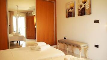 Un dormitorio con una cama grande, un banco y dos cuadros en la pared.