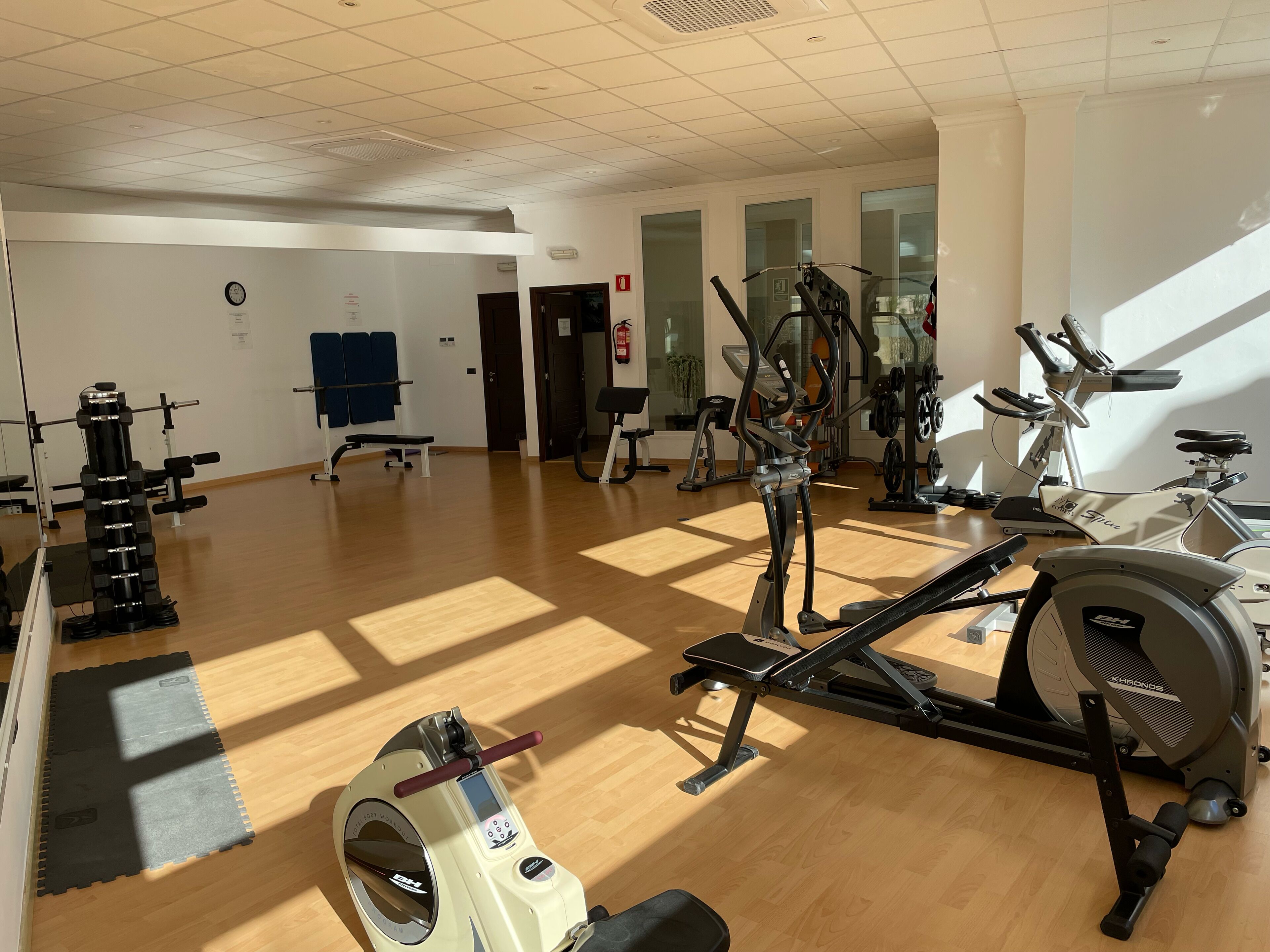 Un gimnasio con diversos equipos de ejercicio, incluyendo cintas de correr, bicicletas estáticas y máquinas de pesas.