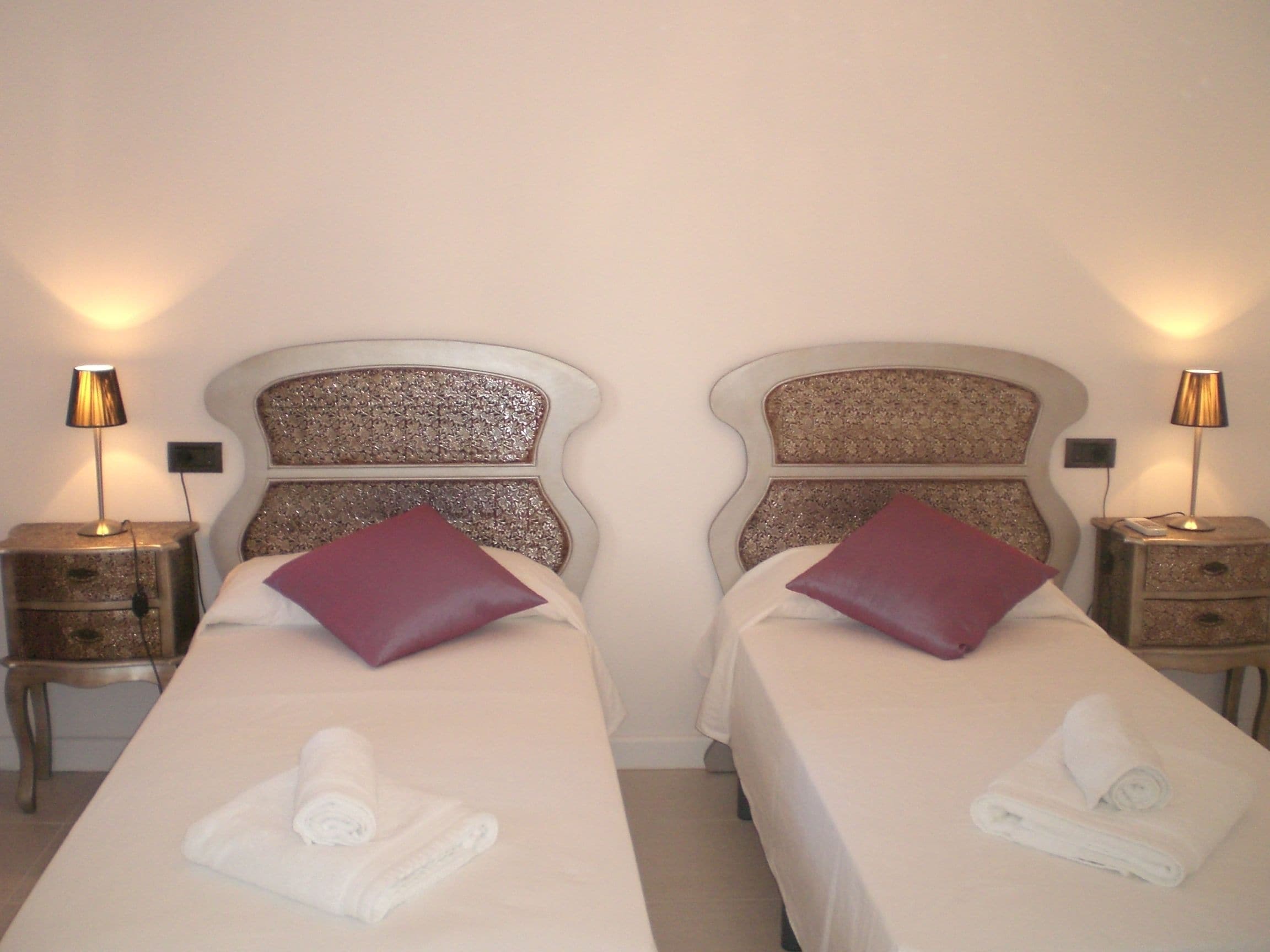 Two beds with headboards, each with a lamp on a bedside table.