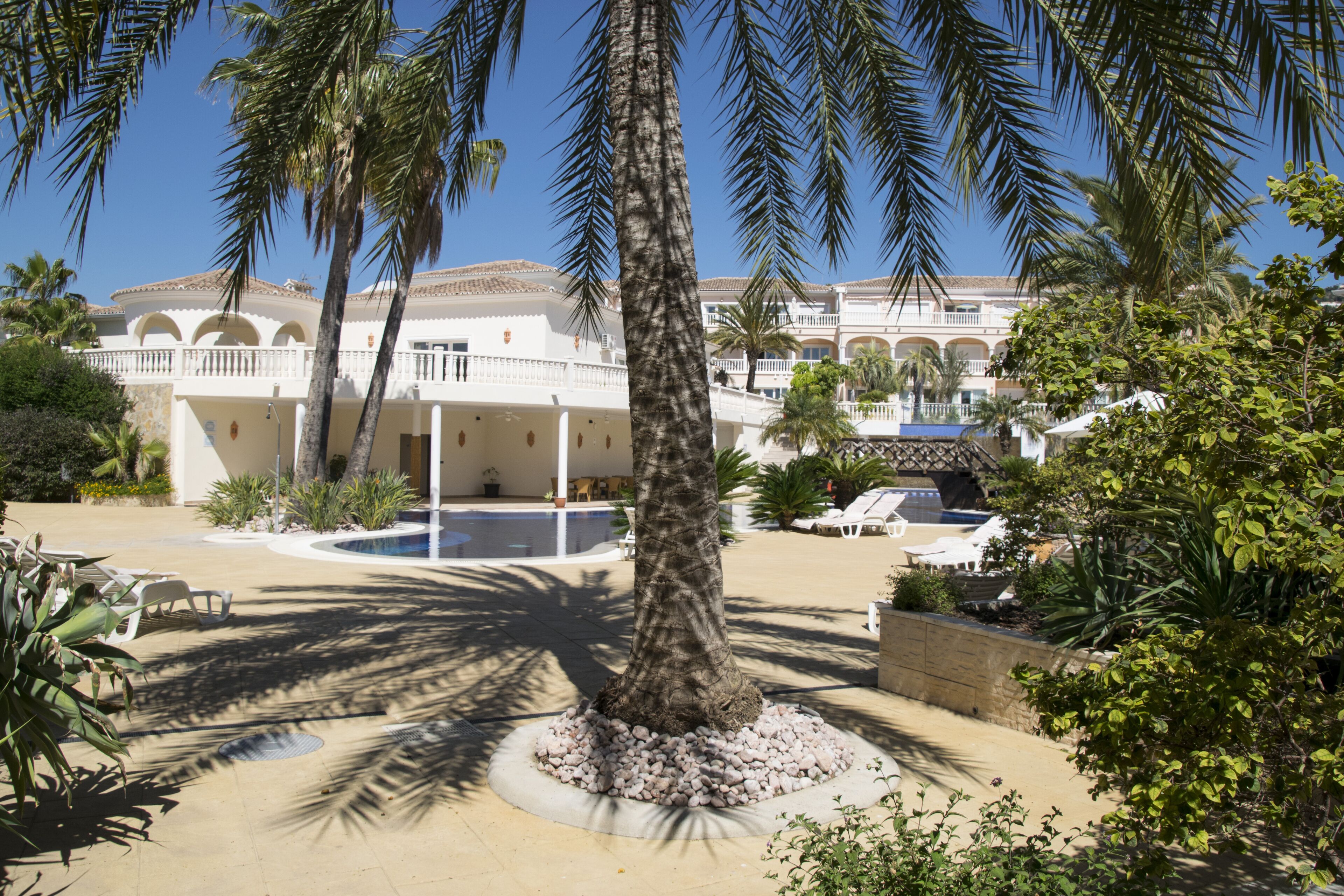 Ein Resort mit Pool, Palmen und einem Gebäude mit Bögen.