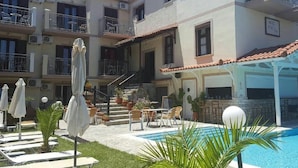 A hotel with a swimming pool, outdoor seating, and multiple balconies. - Matina Hotel (Samos)