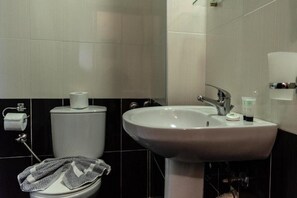 Un baño con inodoro, lavamanos y perchero para toallas.