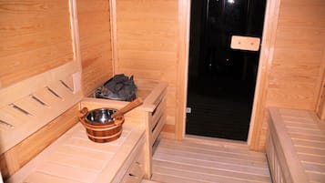 Un sauna con paredes de madera, un banco, un cuenco de madera y un perchero.