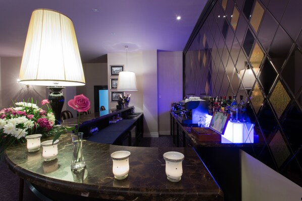 A bar area with a marble countertop, candles, and a large lamp.