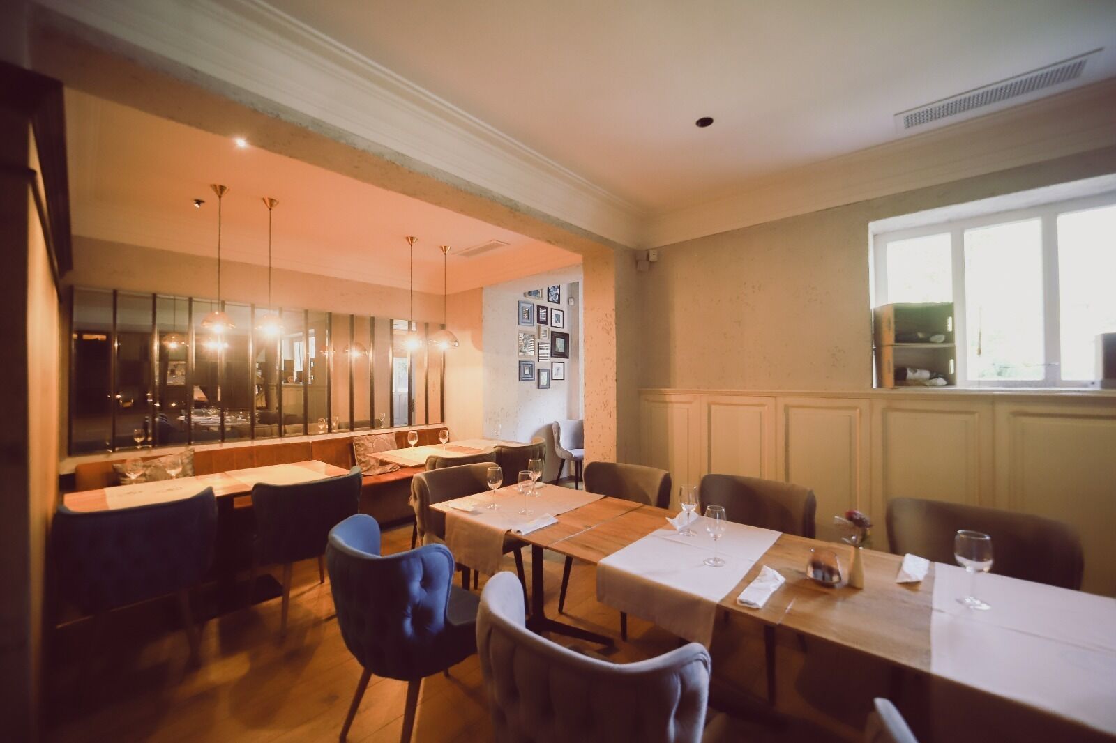 Un comedor con una mesa larga, varias sillas y una lámpara de araña moderna.