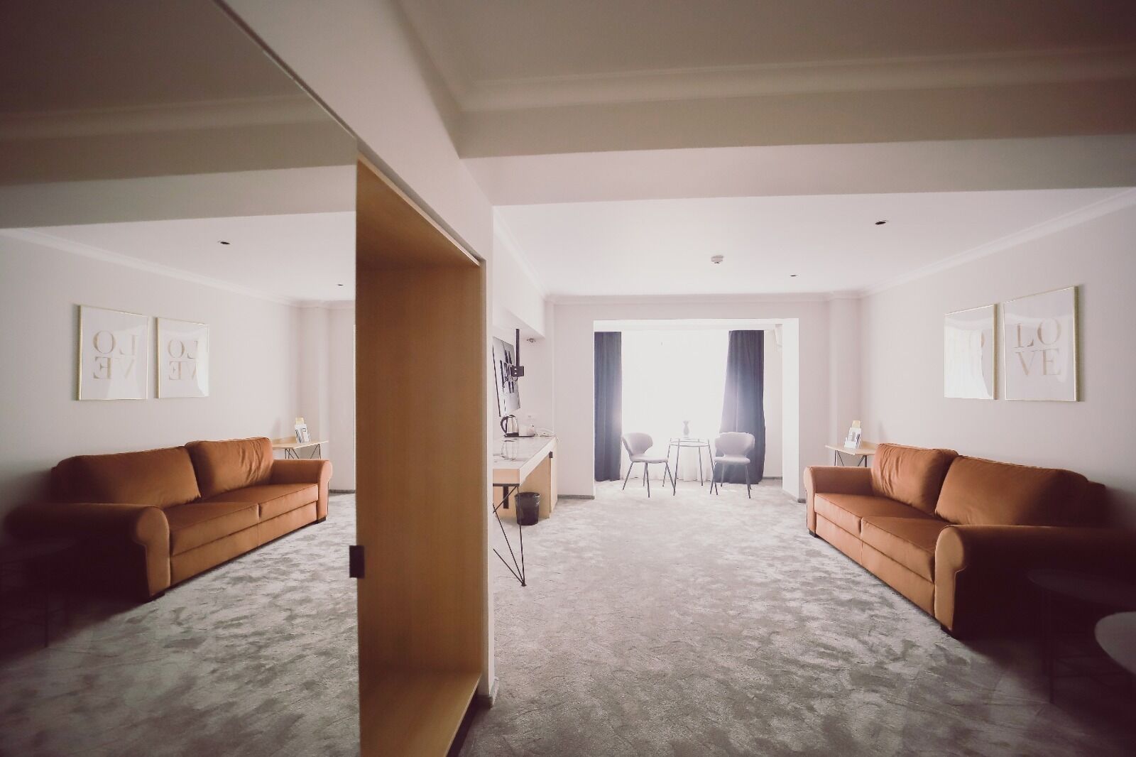 A spacious living room with two brown sofas, a coffee table, and a dining area with two chairs.