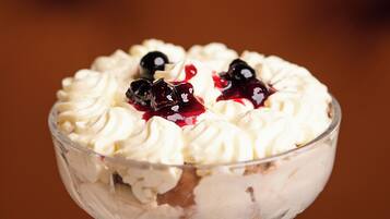 A dessert in a clear glass bowl with whipped cream and berries.