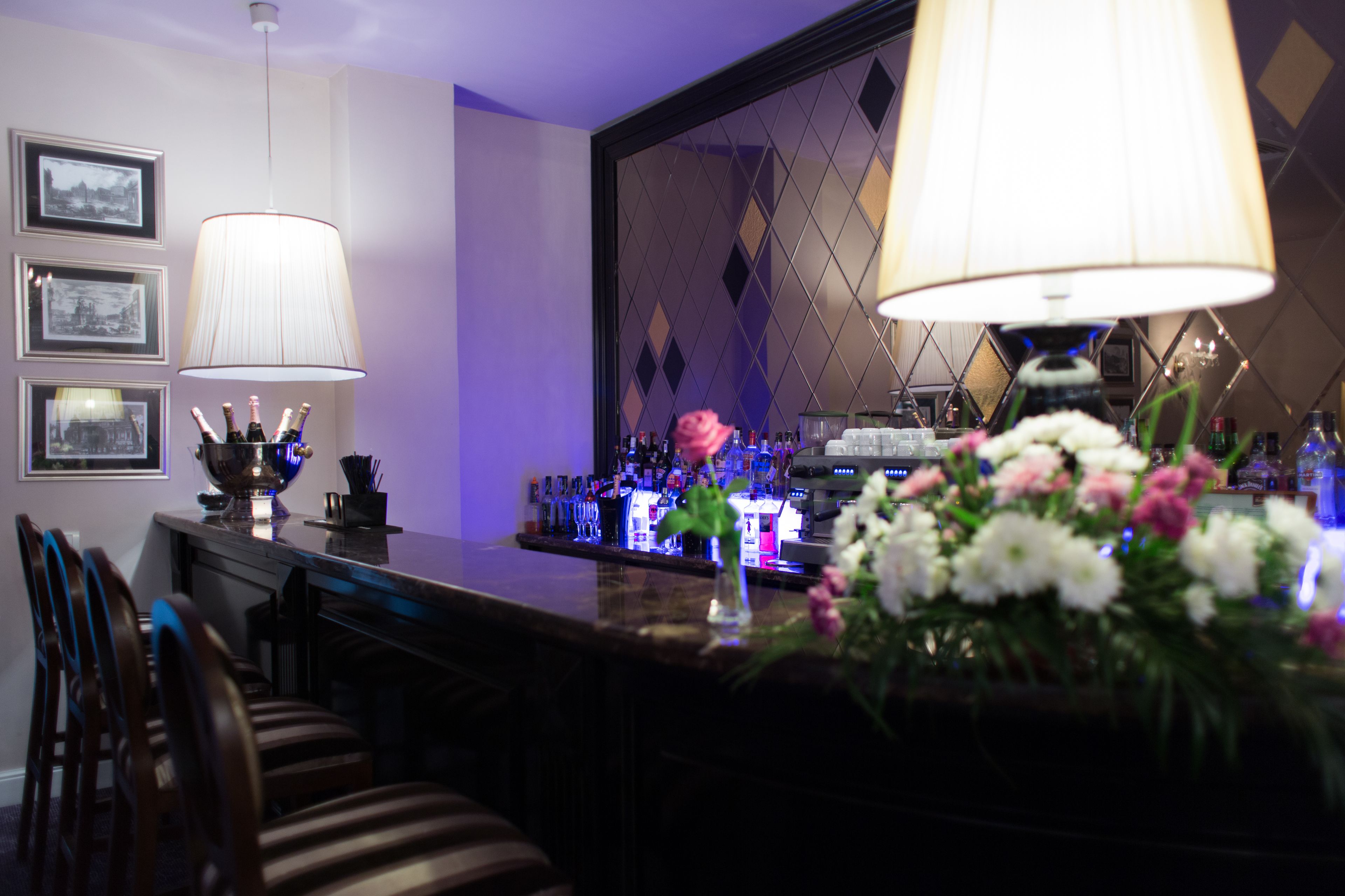 Uma área de bar com balcão, cadeiras e um arranjo floral.