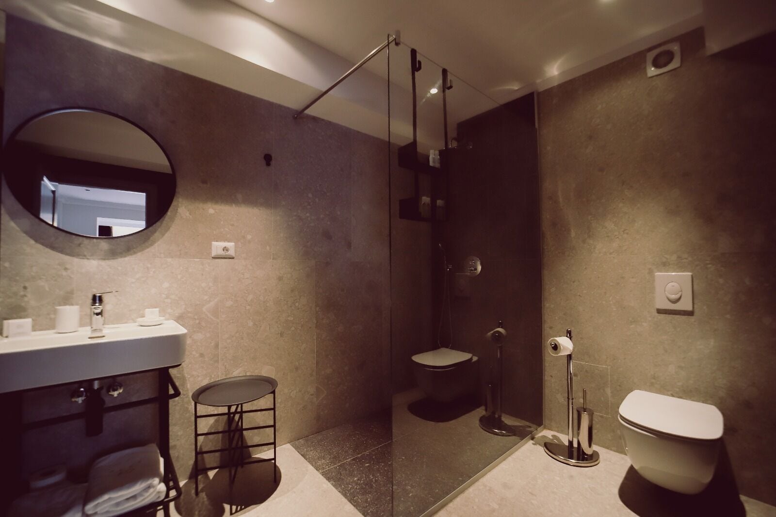 Un baño moderno con lavamanos, inodoro y ducha.