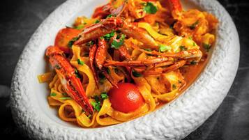 A dish of pasta with shrimp and vegetables in a white bowl.