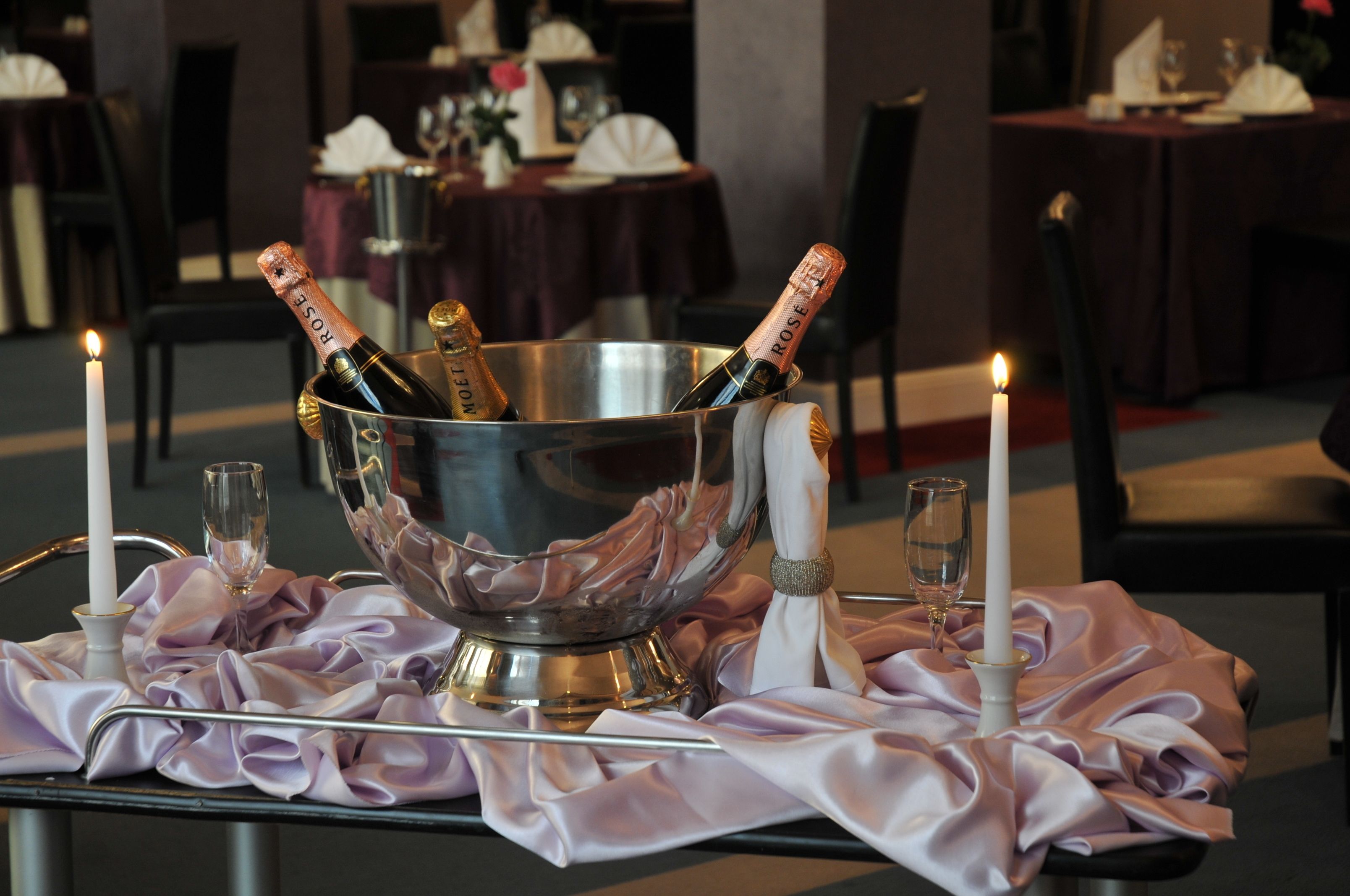 A table set with a champagne bucket, two glasses, and two candles.