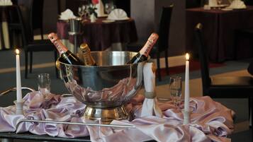 Un tavolo apparecchiato con un secchiello per champagne, due bicchieri e due candele.