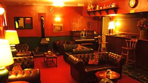 A dimly lit lounge area with leather sofas, a small table, and a bar area in the background.