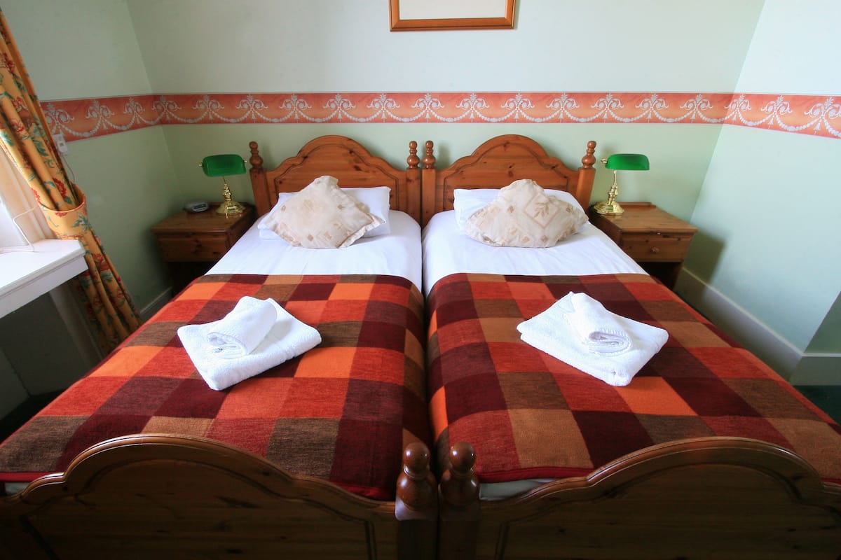 A double bed with a checkered bedspread and two pillows. There are two bedside tables with lamps and a framed picture above the bed.
