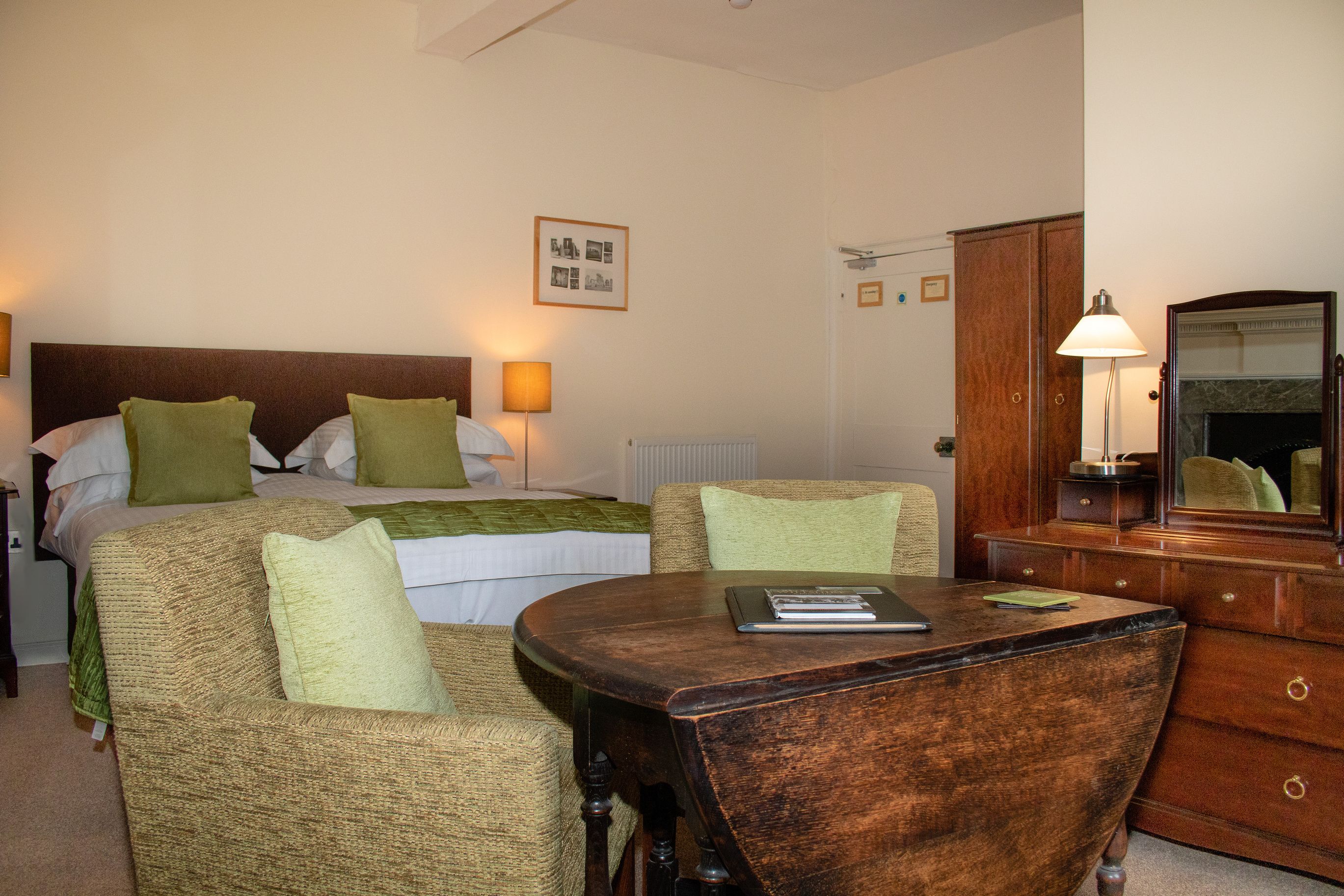 Habitación de hotel con dos camas, una mesa de madera, una silla, un aparador y un espejo.