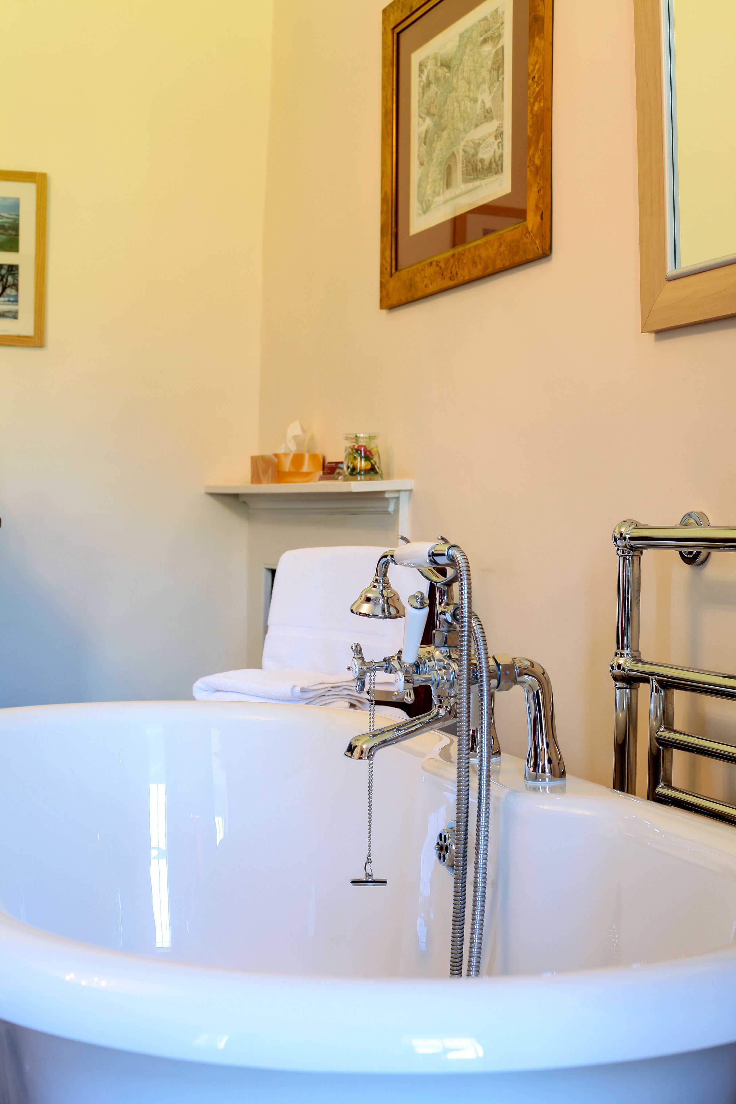 Ein Badezimmer mit einer großen weißen Badewanne, einem Handtuchhalter und einer Ablage mit Pflegeprodukten.