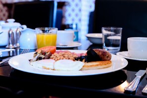 A breakfast plate with eggs, beans, tomatoes, and sausages.
