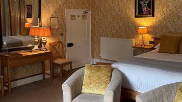 A hotel room with a bed, two armchairs, a desk, and a mirror.