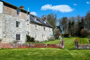 A stone building with multiple windows and a brick wall in front.
