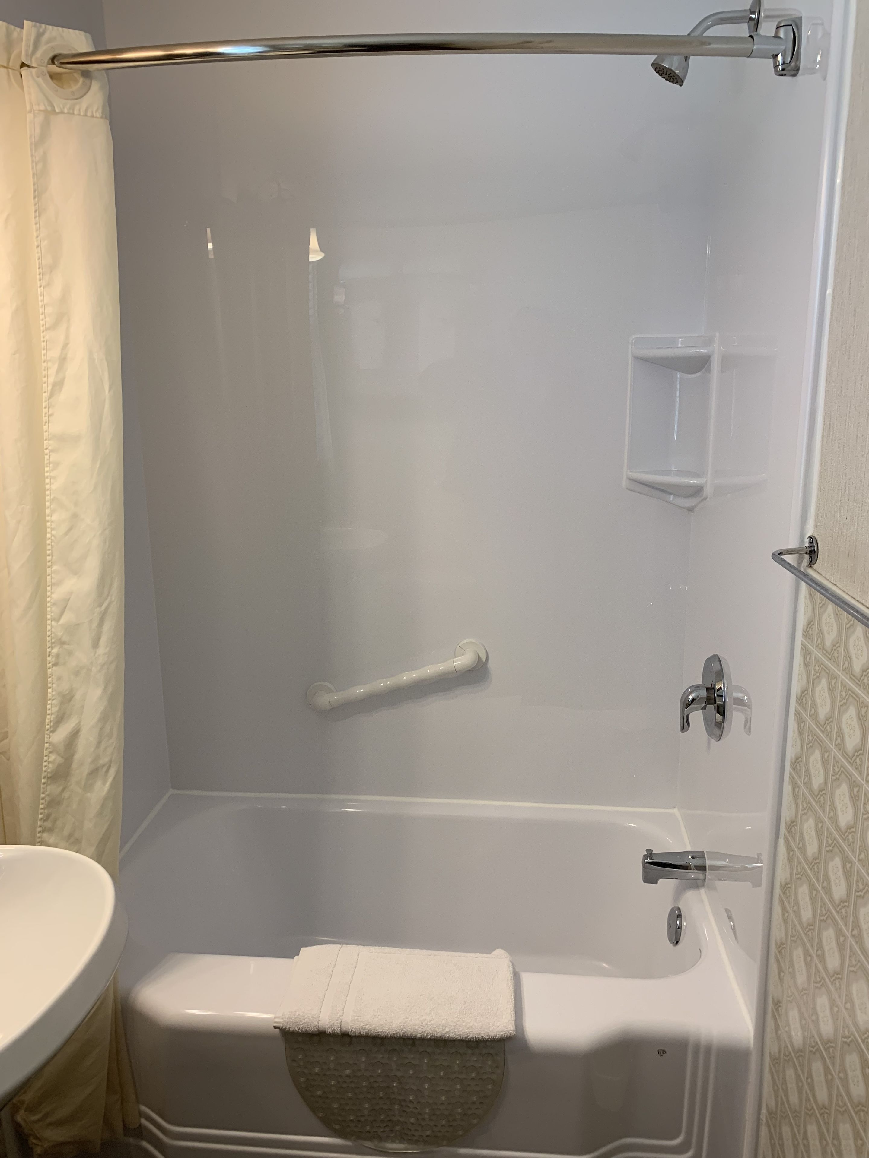 Un baño con bañera, cortina de ducha, toallero, jabonera y retrete.