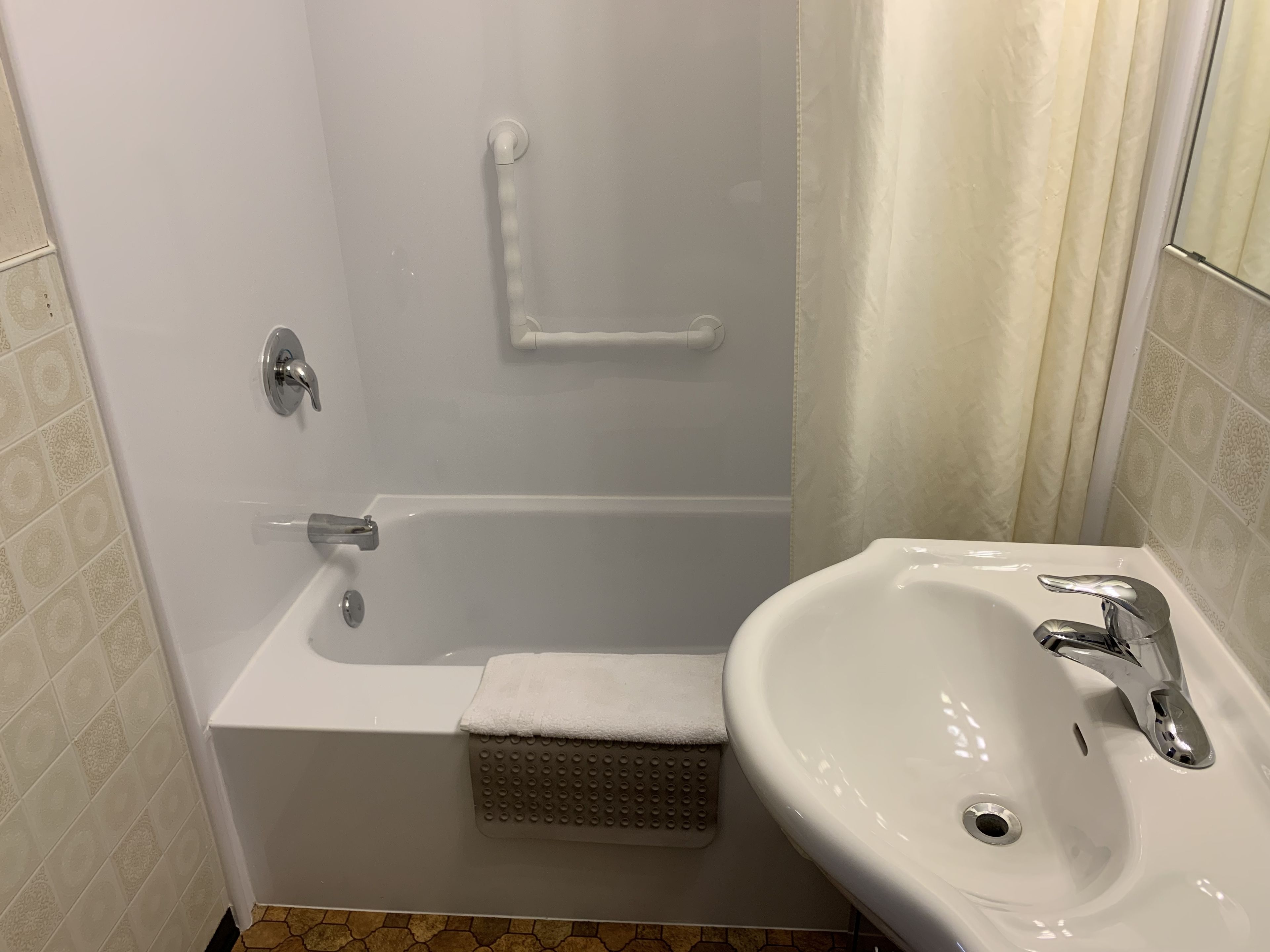 Un baño con bañera, lavamanos y cortina de ducha.