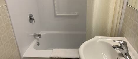 A bathroom with a bathtub, a sink, and a shower curtain.