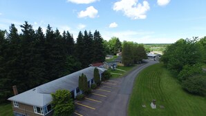 An aerial view of a lodge with a long driveway, surrounded by dense forest. - The Lionstone Inn Motel and Cottages (Pictou)