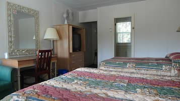 Une chambre à coucher comprenant un lit, un bureau, une chaise, une commode, un téléviseur et un ventilateur de plafond.