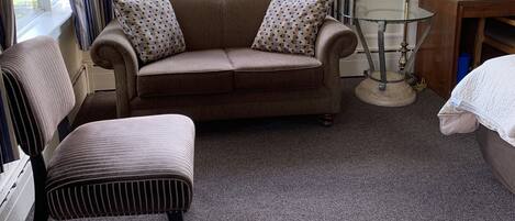 Una habitación acogedora con sofá, una silla, una lámpara y vistas a árboles.