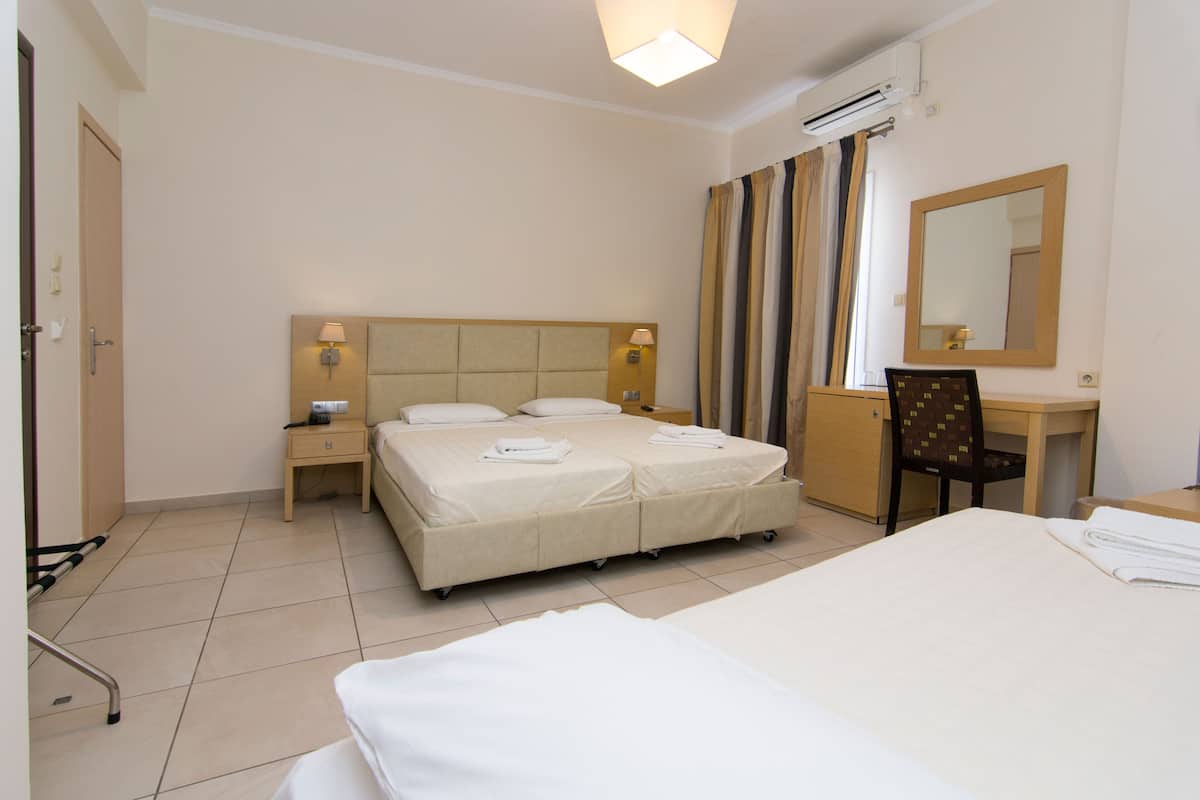 A hotel room with a double bed, a desk, a chair, a nightstand, and a mirror.
