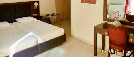 Habitación de hotel con cama, mesita de noche, lámpara, escritorio, silla y espejo.