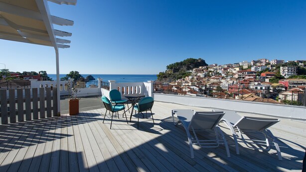 Um deck de madeira com área de estar externa e vista para uma cidade costeira.