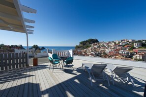 A wooden deck with outdoor seating and a view of a coastal town. - San Nectarios Hotel (Parga)