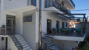 Um hotel com fachada de pedra, escadaria com grades de metal e área de estar externa no andar superior.