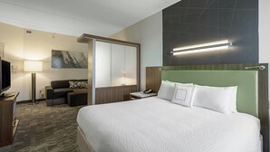 Een hotelkamer met een groot bed, een bureau met een lamp, een televisie en een bank.