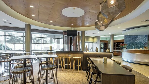 Een modern restaurant met ronde tafels, barkrukken en een bar.