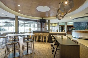 A modern restaurant with round tables, bar stools, and a bar area. - SpringHill Suites by Marriott Tampa North/I 75 Tampa Palms (Tampa)