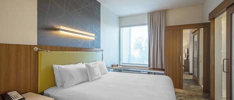 A hotel room with a large bed, bedside table, and a window with curtains.